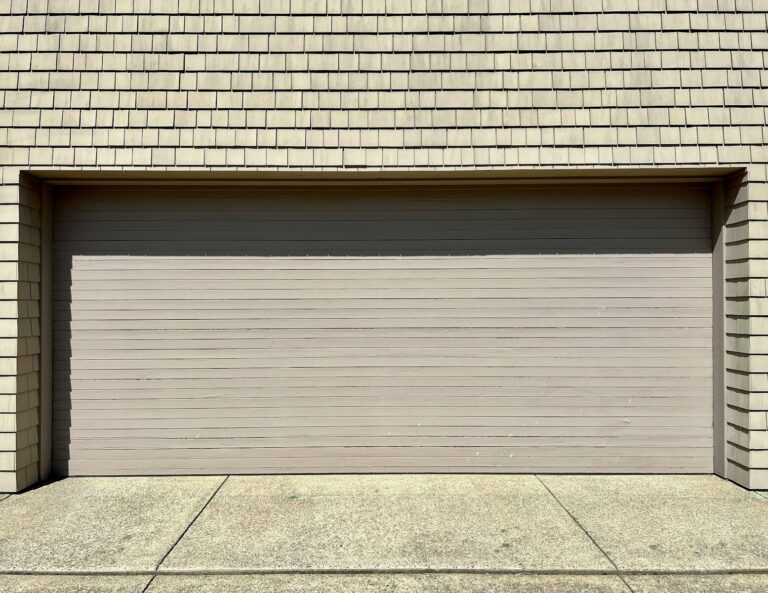 a white fire hydrant sitting in front of a garage door