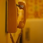 an orange phone is hanging on a wall