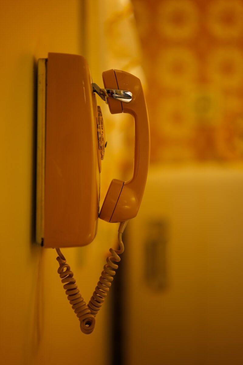an orange phone is hanging on a wall