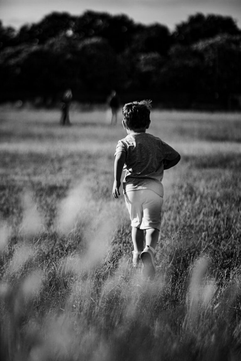 a little boy running through a field of tall grass